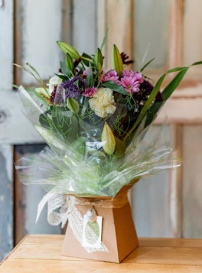 Florist Choice Bouquet - This is our "florist choice" hand-tied bouquet. A seasonal selection of fresh flowers and foliages, often including lilies, chrysanthemums, limonium, gypsophila, alstromeria, lisianthus, statice, freesia, roses, ruscus, eucalyptus, cocculus, beregrass and aspidistra leaves. Your florist will select and arrange the best flowers available, spiralling the stems and tying them with twine. We will wrap them in a water reservoir and put them into a cardboard transporter vase ensuring that they arrive at their destination in tip top condition. Vase colours may vary between natural kraft, soft grey or sage green, and will often be finished with a pale coloured raffia tie or a toning ribbon bow. The hand-tied bouquet is our most popular gift as they always look natural, classic and stylish, making them ideal for a birthday or thank you gift, as a way to say "I love you" or "Get well soon".